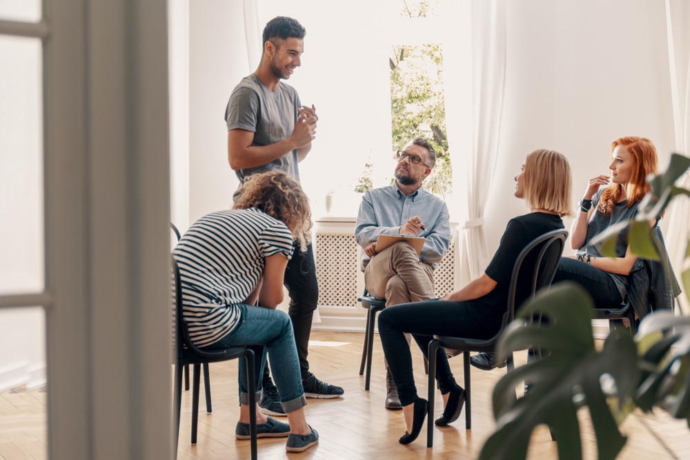 Man stands up to speak during group therapy session.