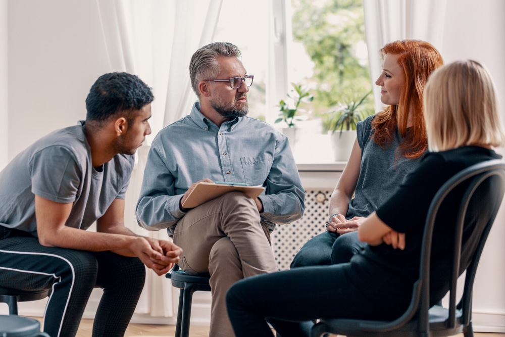 A counselor talks during a group therapy session.