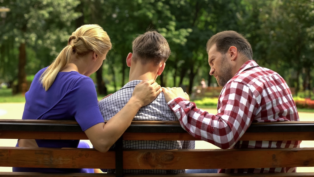 Parents talk to their teen son in the park.