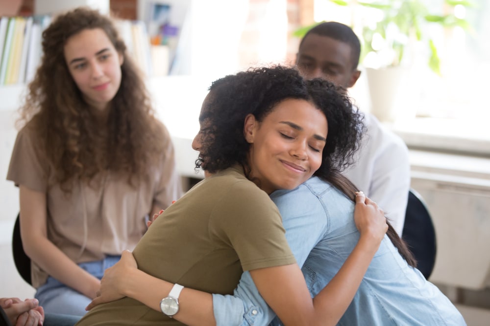 Two women hug during a therapy session.