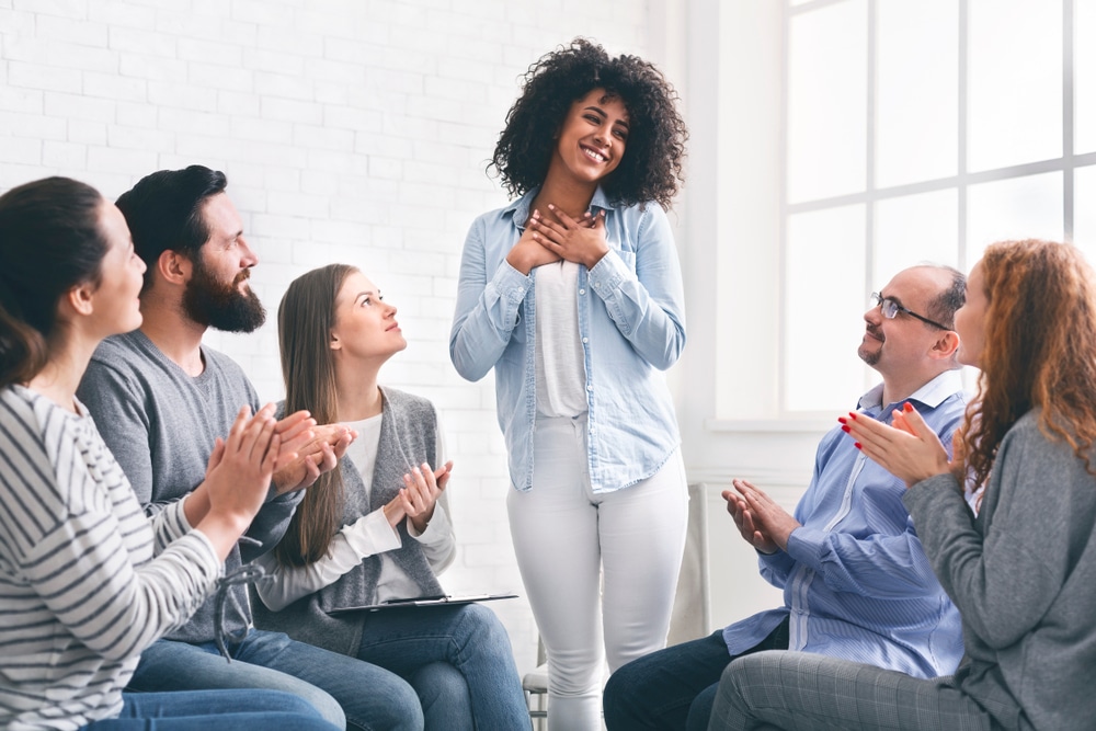 Woman stands up to speak during group therapy session.