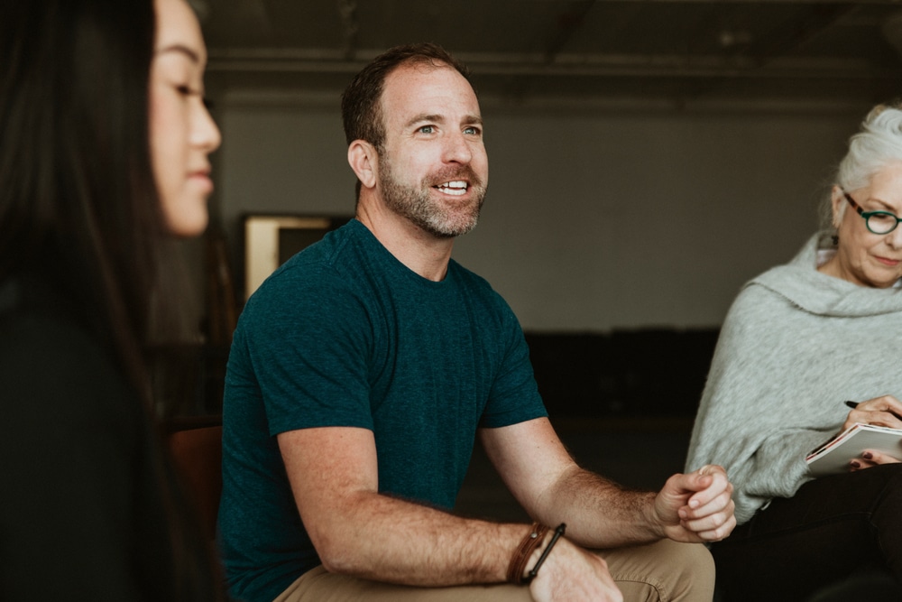 Man smiles in group therapy session.