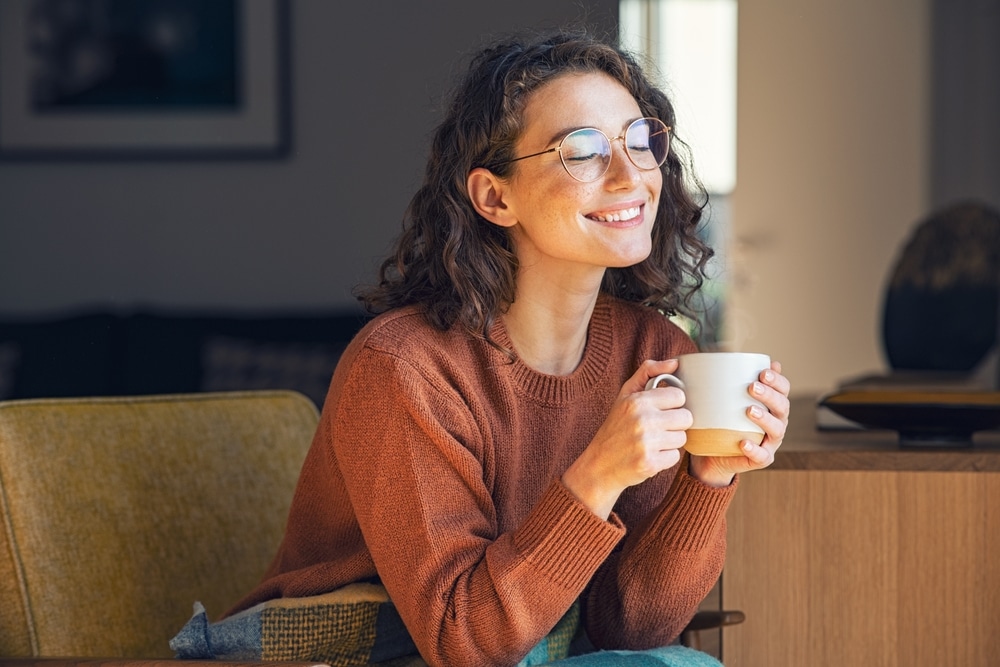 Woman holds a cup of tea and relaxes at home.