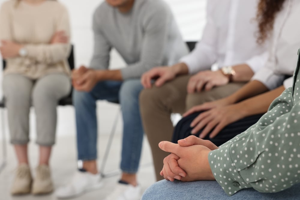 Closeup of hands of a group of people sitting in group therapy.