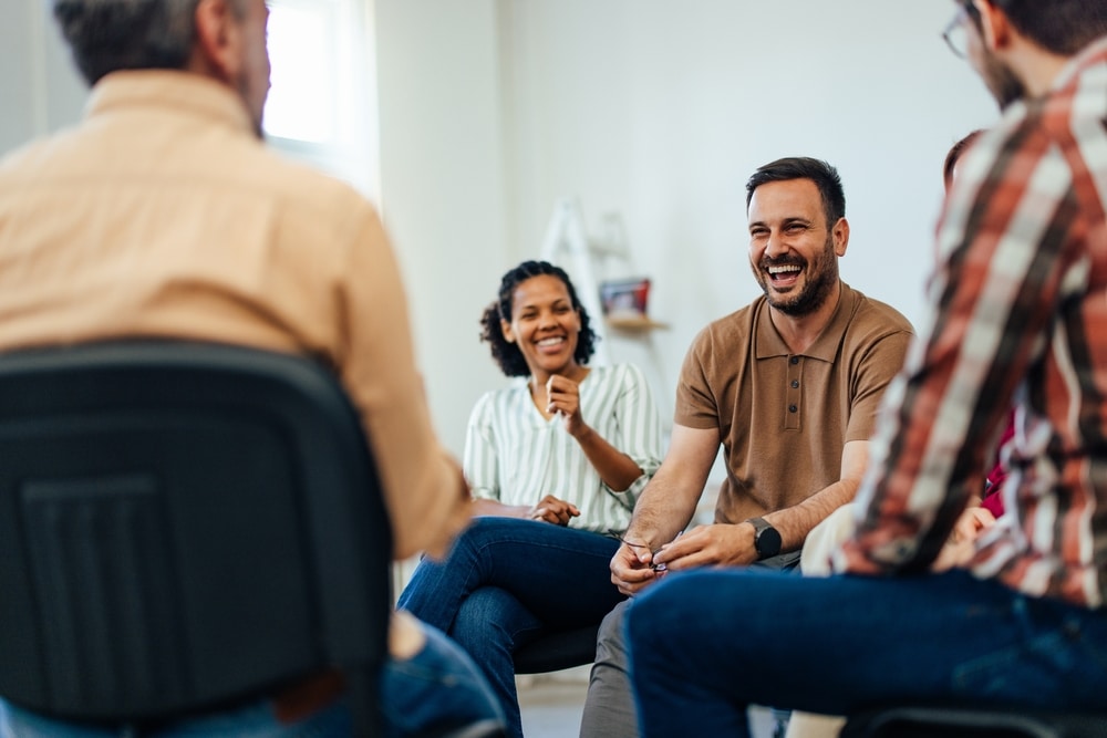 People laugh in a group therapy session.