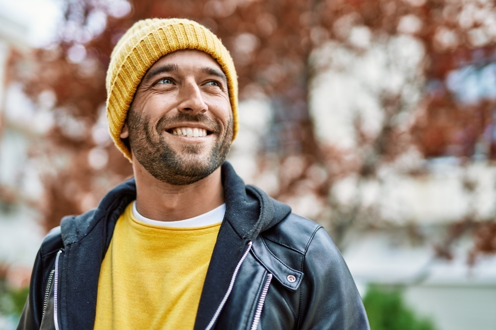 Happy man smiles while standing outside.