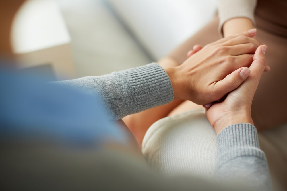 Closeup of two people holding hands.