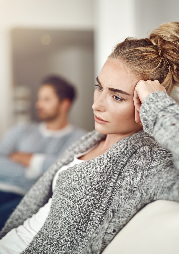 A woman looks upset while sitting on a couch.