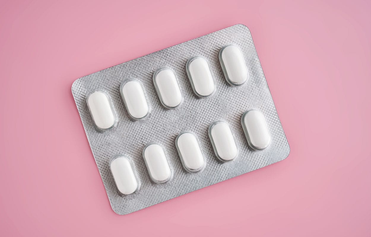 Is Tramadol Addictive? A blister pill packet with white pills sitting on a pink surface.