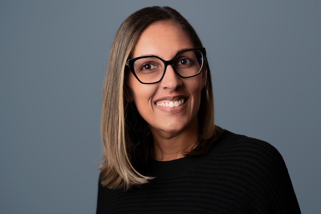 Person wearing black glasses and black top smiling.