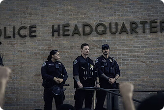 Police officers standing in front of a police headquarters building.