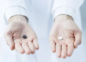 Gabapentin and ibuprofen. Person holding two different types of pills.