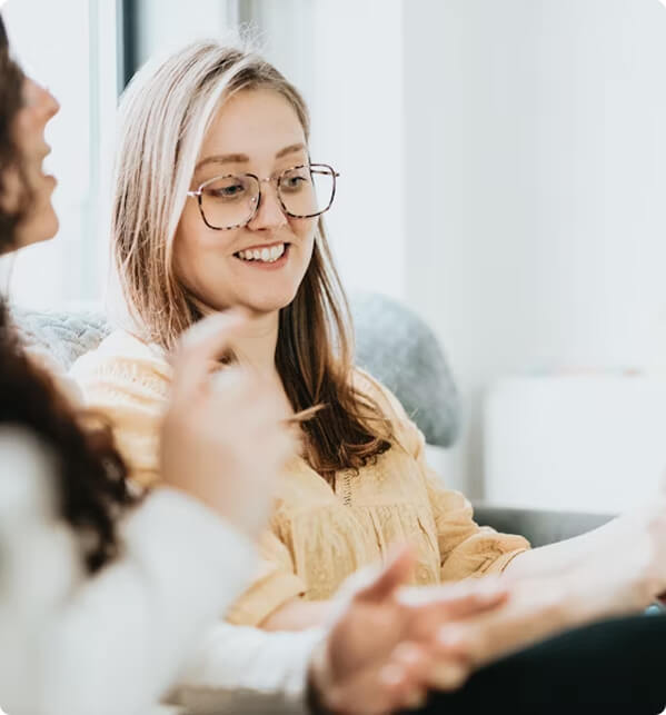 Person wearing glasses and yellow blouse, smiling while sitting.