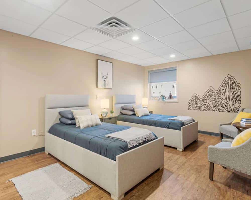 Two twin beds in a neatly arranged room with a mountain wall mural and modern decor.